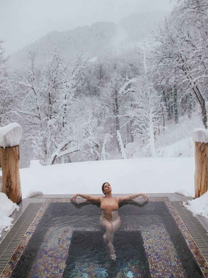 about-01 A woman enjoys a thermal pool surrounded by winter snow and nature.